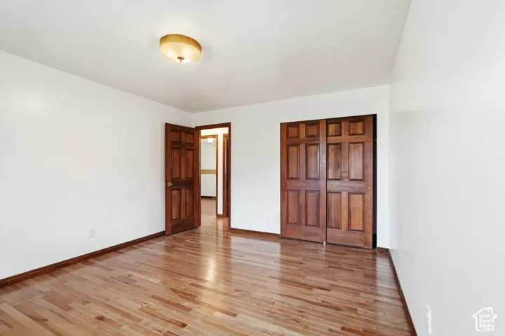 Room featuring wood-finish flooring, six-panel wood doors, sliding-door closet, and dome-style flush mount ceiling lighting