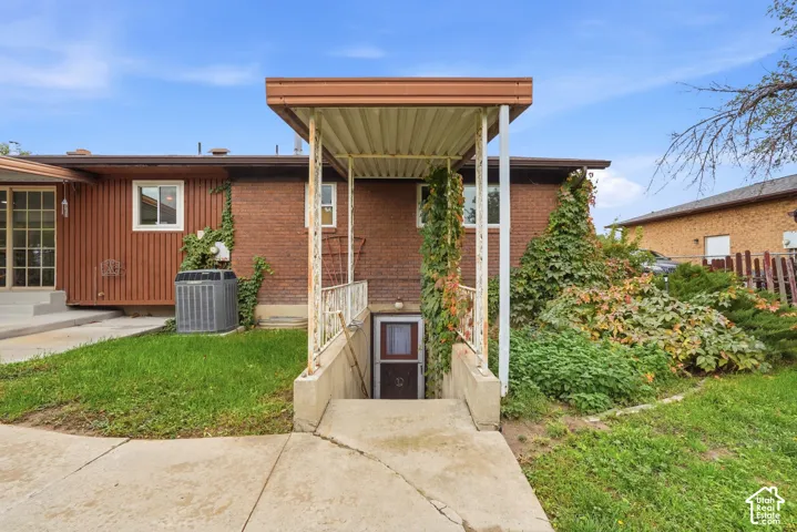 Brick exterior featuring a covered basement stairwell entry with decorative iron railings