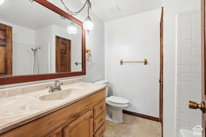 Bathroom featuring a wood vanity with integrated basin, expansive wall-mounted mirror, dual globe-style hanging light fixtures, and ceramic tile flooring