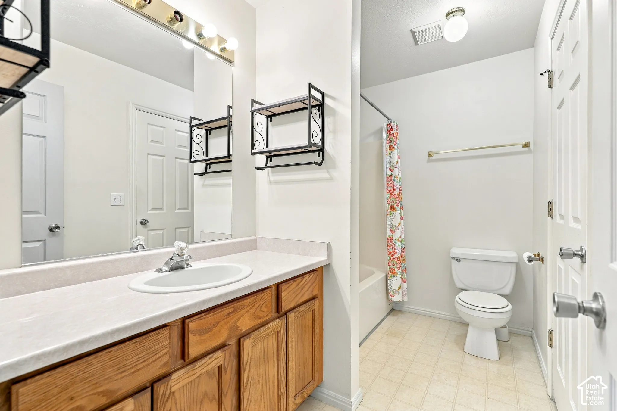Bathroom with a wood-finish vanity, integrated sink, and full-width mirror