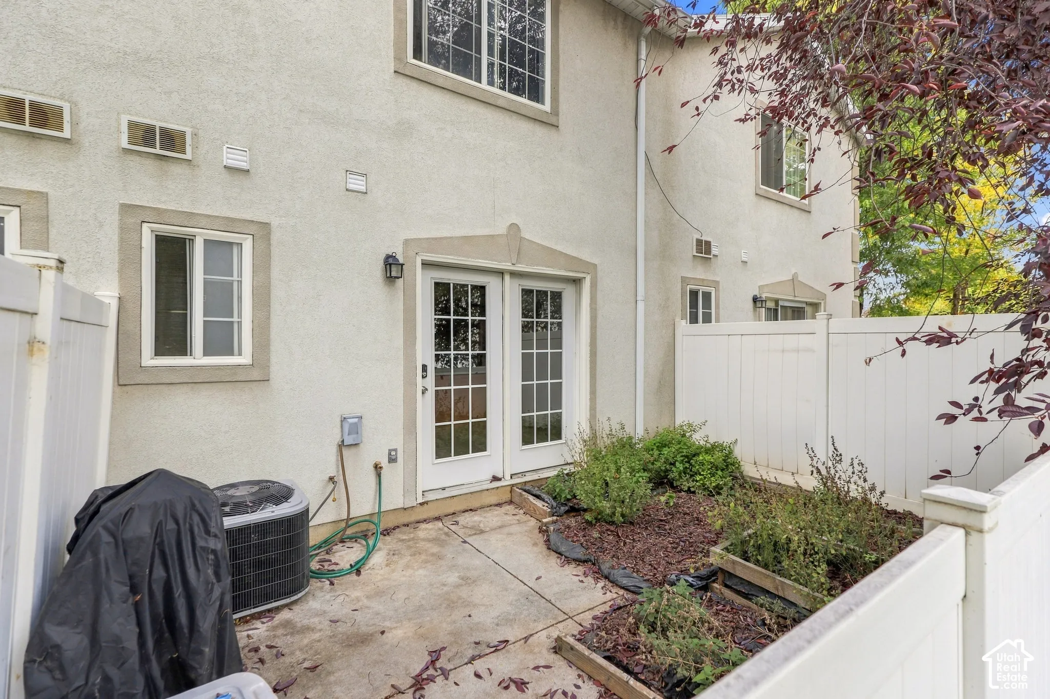 Private patio with concrete flooring, framed by white privacy fencing