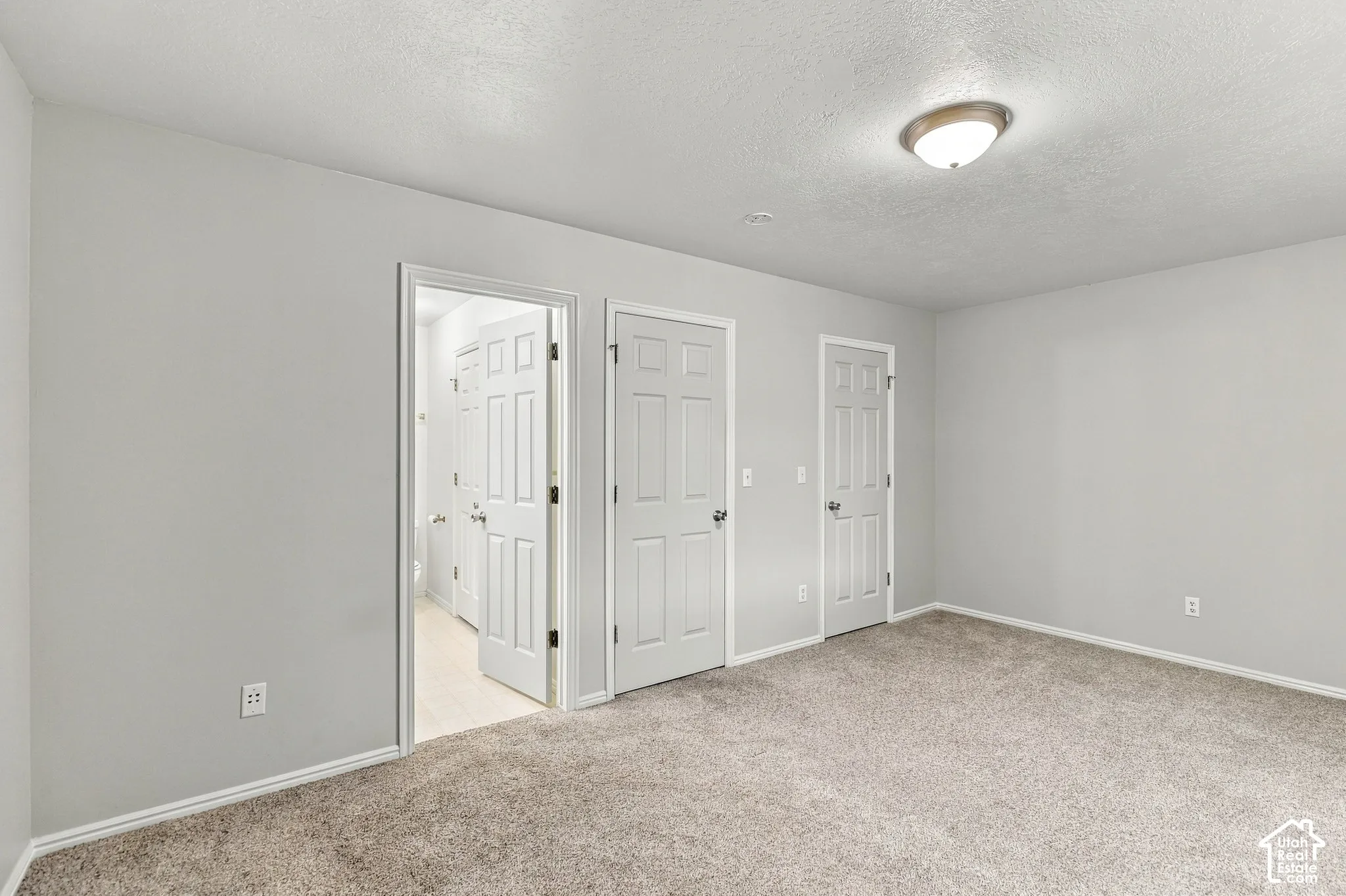 Spacious bedroom retreat showcasing neutral wall finishes, plush carpeting throughout, recessed ceiling lighting, and multiple six-panel closet doors providing generous storage solutions