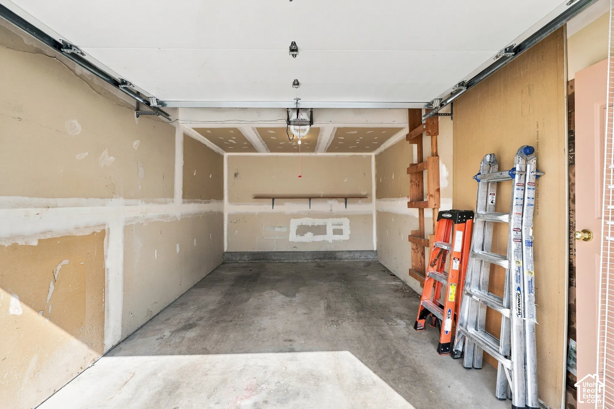 Concrete flooring, drop ceiling, built-in shelving, and exposed ceiling joists