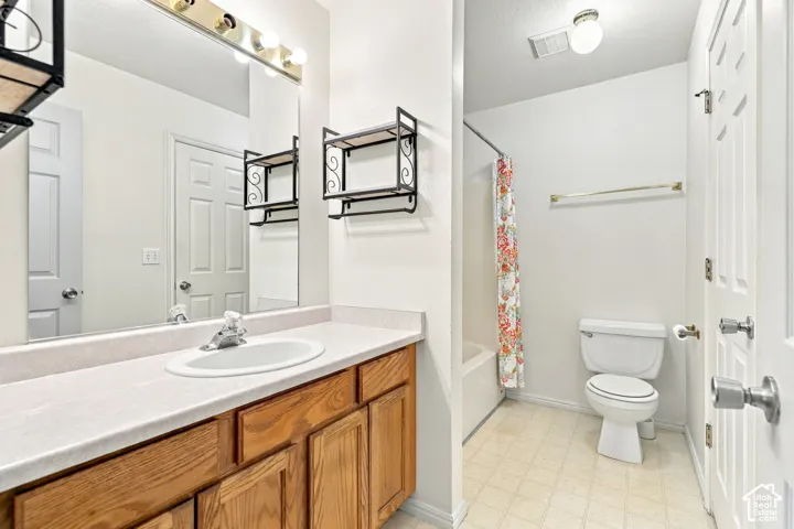 Bathroom with a wood-finish vanity, integrated sink, and full-width mirror