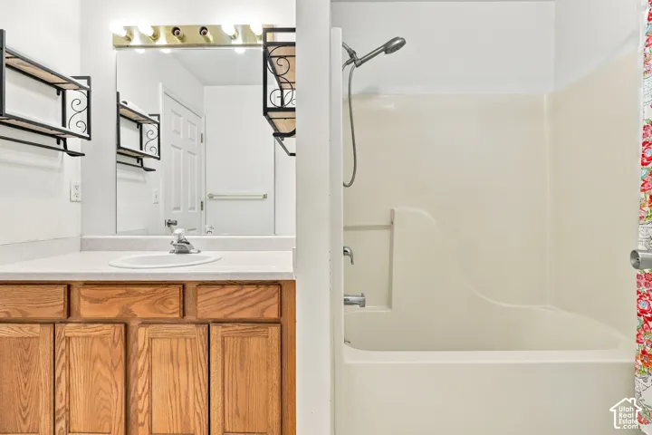 Master bathroom featuring a wood-finish vanity with multiple storage drawers, white quartz countertop, and chrome faucet