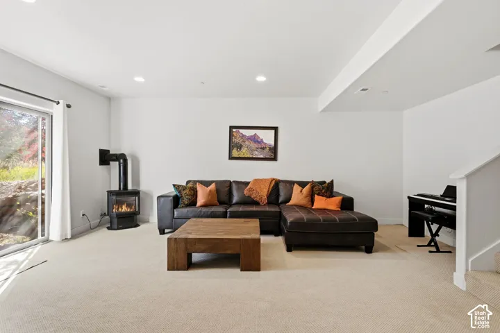 Recessed lighting, light-toned carpeting, and a built-in wood-burning stove with a glass door