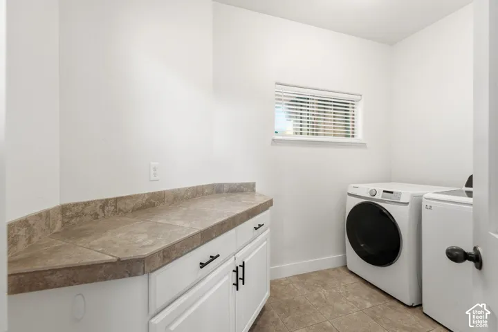 Built-in cabinetry with matte black hardware, tile countertop, window with blinds, and tile flooring