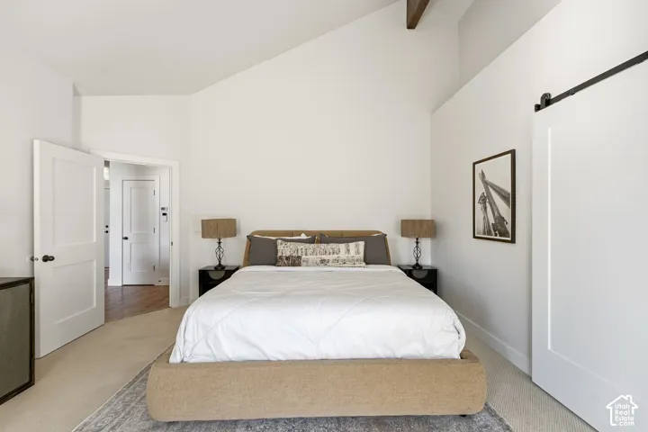 Vaulted ceiling with exposed wood beams, white paneled doors with matte black hardware, and a sliding barn door