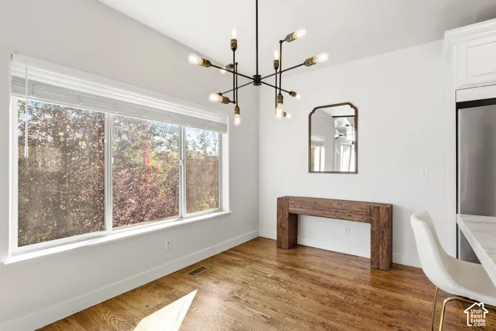 Hardwood flooring, expansive window, modern chandelier, white walls, built-in cabinetry