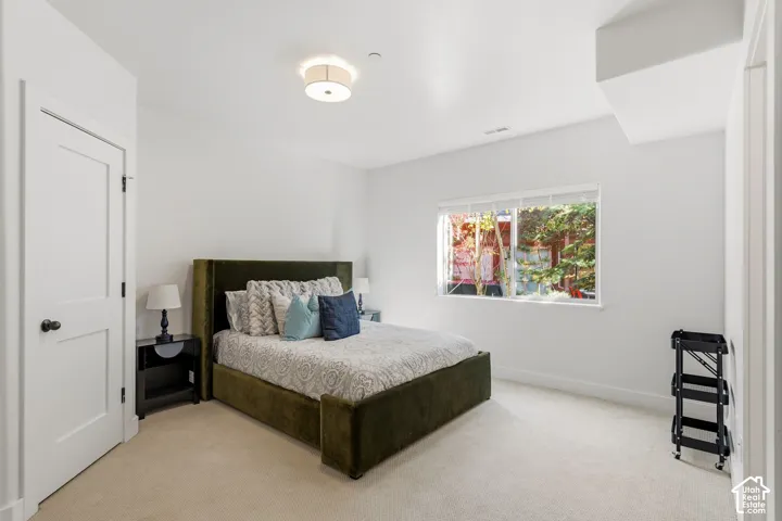 White walls, light neutral carpeting, and a flush-mount ceiling light provide a bright interior