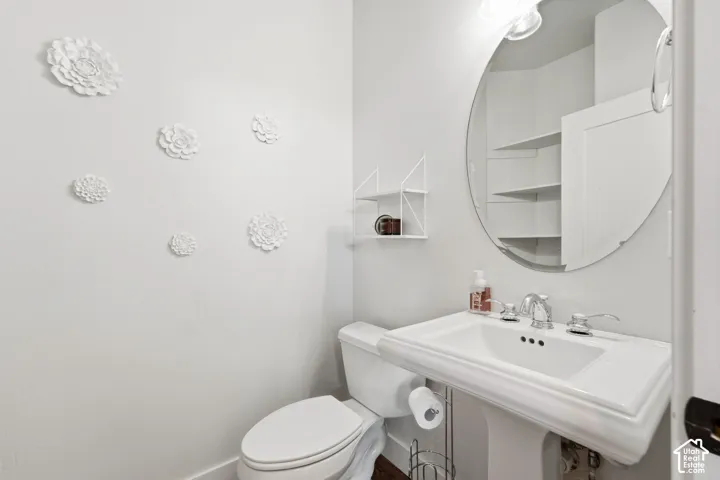 Pedestal sink with chrome fixtures, wall-mounted oval mirror, and built-in shelving