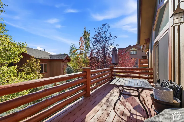 Wood-finish deck with log railing, a sliding glass door, and an exterior wall lantern