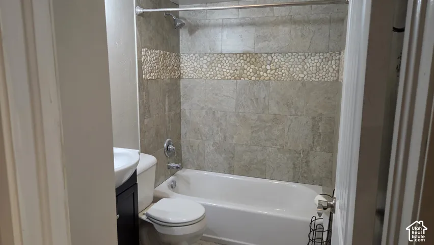 Bathtub with tiled surround, decorative pebble tile accent, and a shower fixture