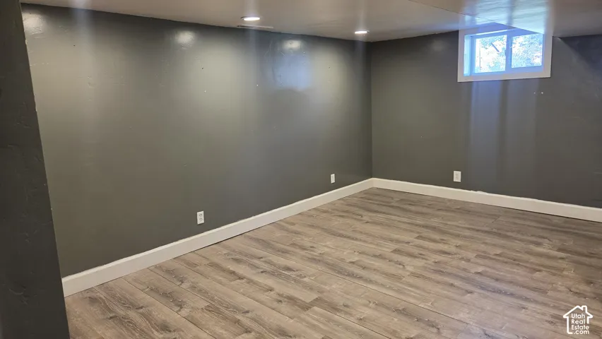 Recessed lighting, wood-finish flooring, white trim, and a window