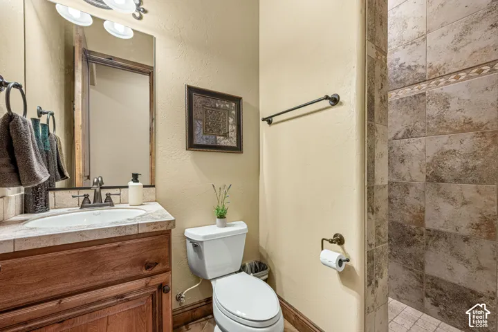 Wood vanity with a tile countertop, undermount sink, and bronze faucet