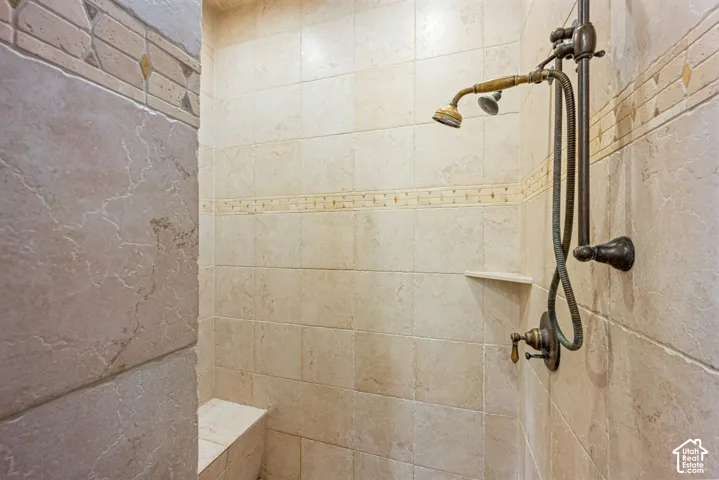 Tiled shower enclosure featuring a built-in bench, corner shelf, and an antique brass-finish shower system
