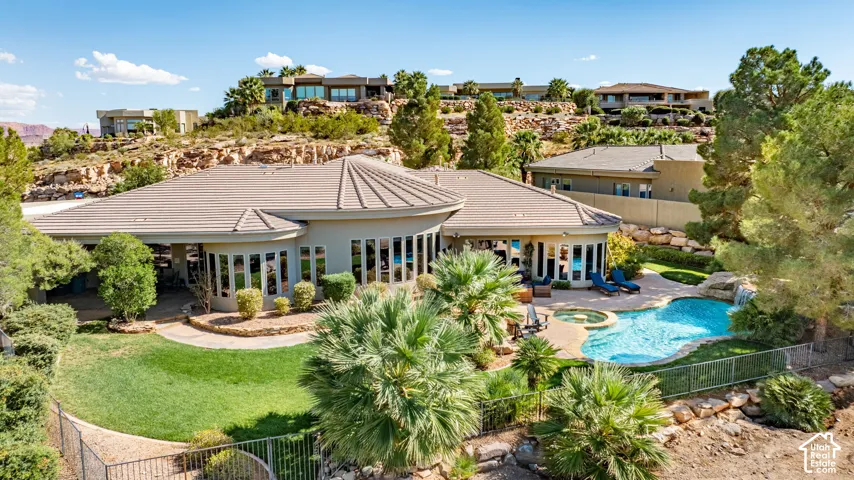 Expansive rear elevation with extensive glazing, a curvilinear swimming pool, an integrated spa, a rock waterfall feature, and established landscaping