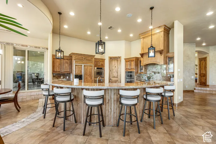 Expansive curved island with wood paneling and stone countertop, complemented by custom wood cabinetry and an integrated range hood