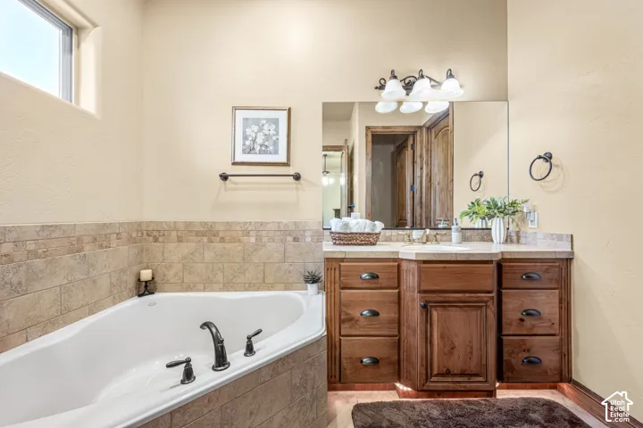 Built-in soaking tub with dark bronze fixtures, integrated tile surround, and an upper transom window