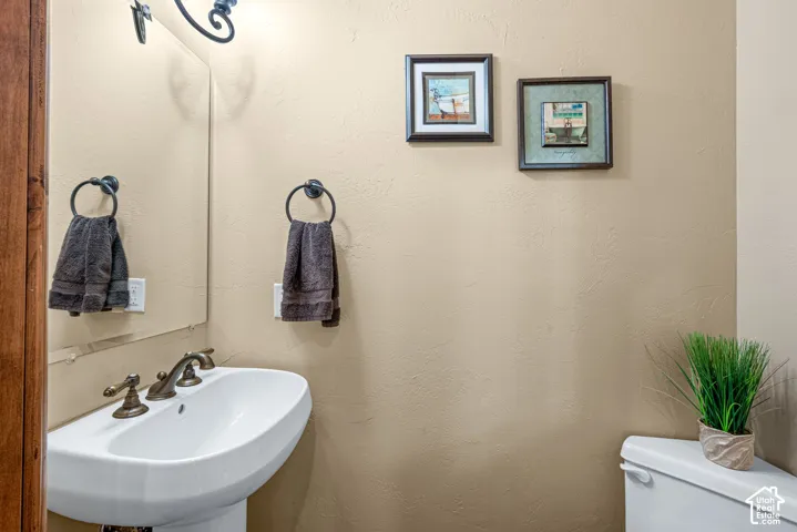 White pedestal sink with a bronze-finish faucet, accompanied by a toilet