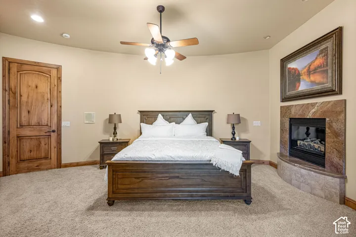 Recessed lighting, ceiling fan, natural wood door, fireplace with stone surround, and light-toned carpeting