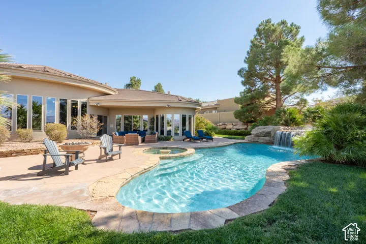 Custom-shaped swimming pool with an integrated spa, rock waterfall feature, and surrounding concrete patio