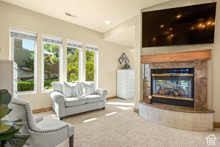 Recessed lighting, broad windows, a gas fireplace with a stone surround, and carpeting