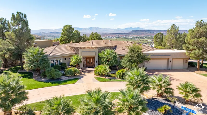 Stone and stucco exterior with a multi-car garage, mature landscaping, and a substantial driveway