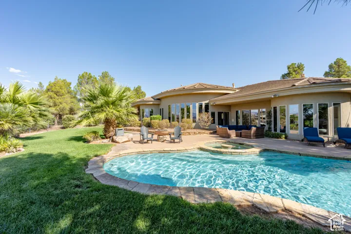 Expansive backyard featuring a curved swimming pool, integrated spa, and surrounding patio space