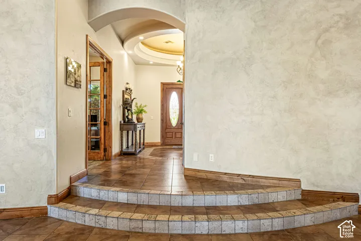 Tiered tile steps with wood trim, curved arched doorway, and layered ceiling with recessed lighting