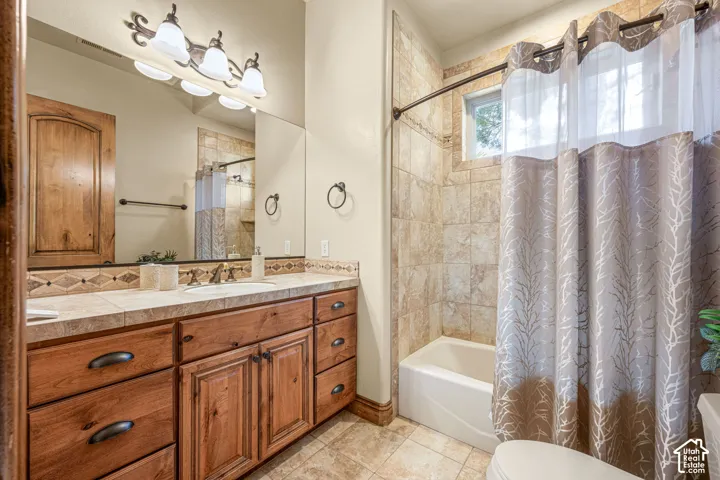 Wood-finish vanity with an integrated sink, tile countertop, and decorative backsplash