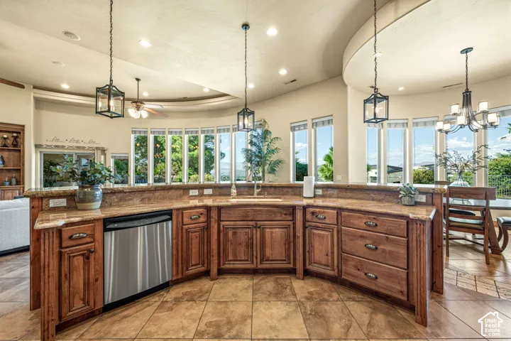 Curved kitchen island with wood cabinetry, integrated stainless steel dishwasher, and a built-in sink with a gooseneck faucet