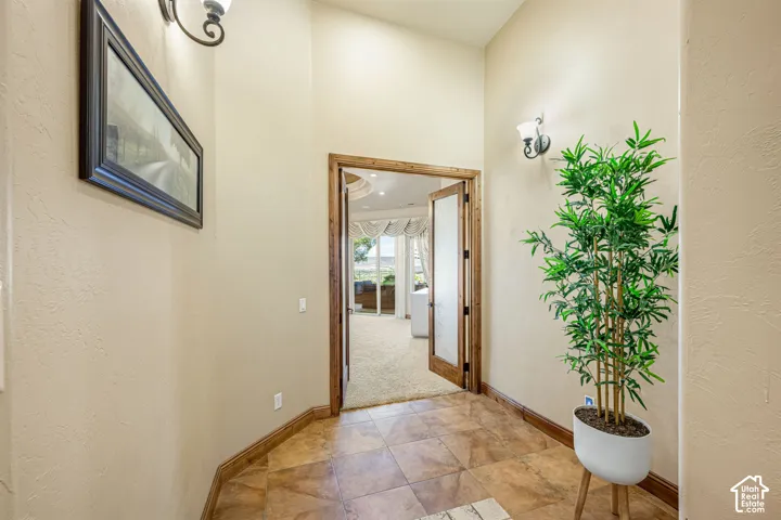Tiled flooring with a warm finish, wood-trimmed doorway, and wall sconces