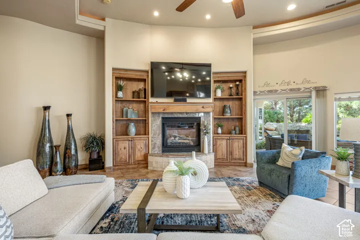 Curved wall with recessed lighting, built-in fireplace with stone surround, custom wood built-in shelving, vaulted ceiling with a ceiling fan, and sliding glass doors