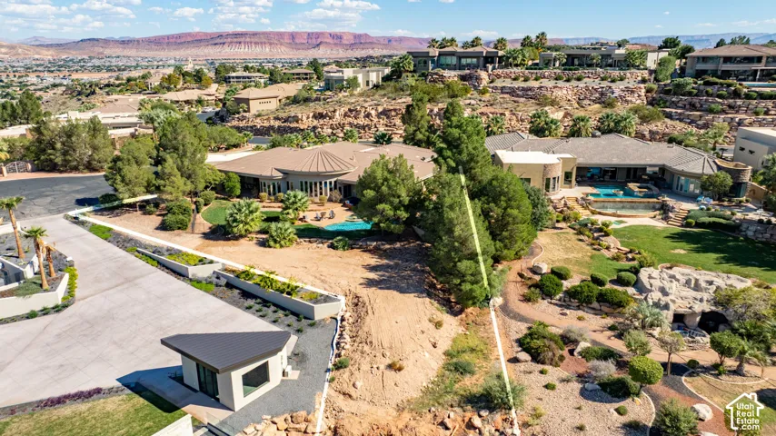 Expansive property featuring multiple structures, a terraced landscape with mature trees, a curvilinear swimming pool, and a dedicated entry structure
