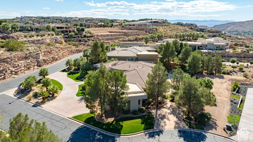 Expansive property featuring a curved driveway, mature trees, and a terraced landscape