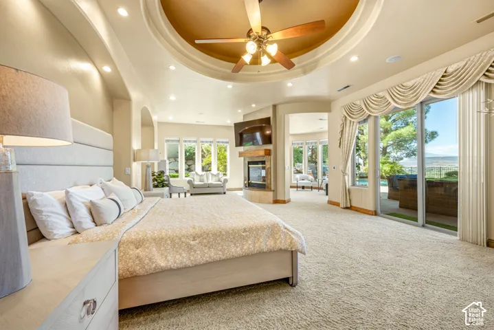 Recessed lighting, arched doorways, a ceiling fan, a fireplace with a wood mantel, and sliding glass doors with custom drapery