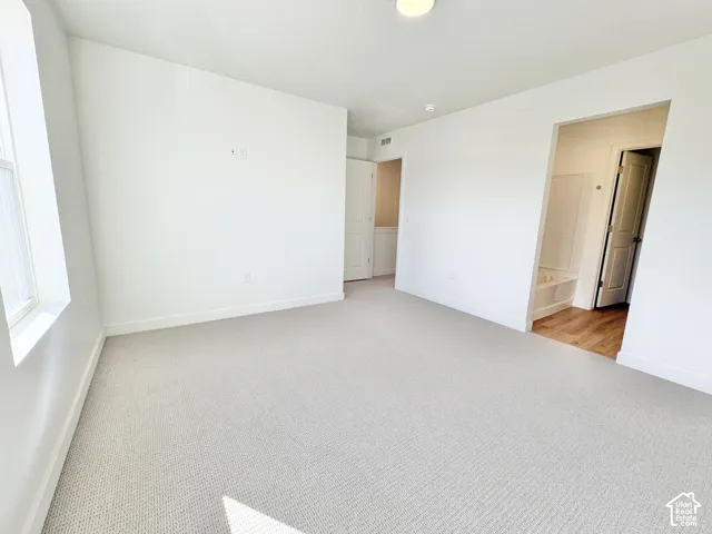 Neutral-toned carpeting, white walls, and a window providing natural illumination