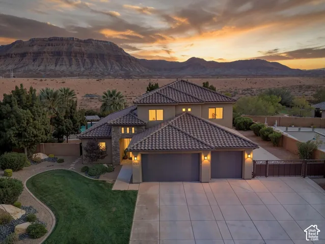 Stucco exterior with stone accents, concrete tile roofing, and a substantial driveway
