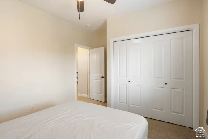 Neutral wall tones with carpeted flooring, featuring a built-in closet with bi-fold doors and a ceiling fan