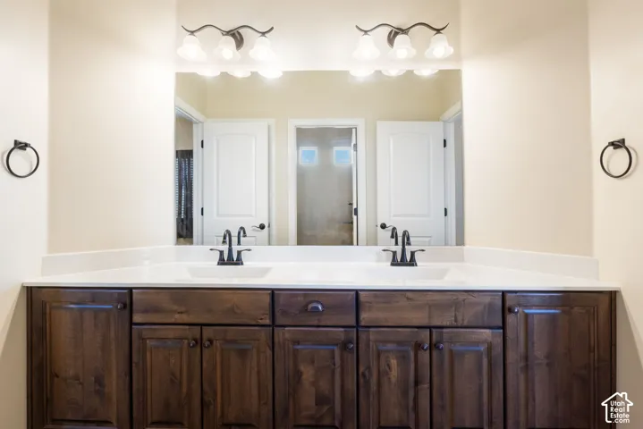 Dual vanity with white undermount sinks, white countertops, and dark wood-finish cabinetry
