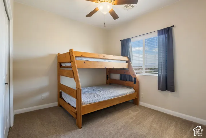 Recessed window with blinds, ceiling fan with light fixture, neutral wall color, and carpeted flooring