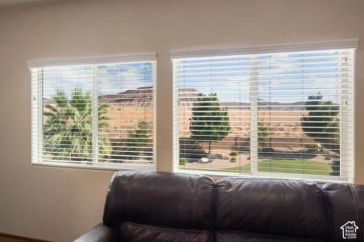Expansive window with horizontal blinds framing a desert landscape and mountainous terrain