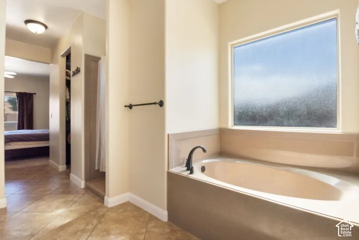 Spacious soaking tub with a dark bronze faucet, set beneath a large privacy window