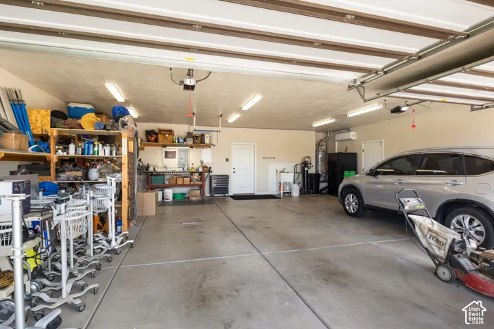 Attached garage with concrete flooring, multiple overhead fluorescent light fixtures, and a white overhead door
