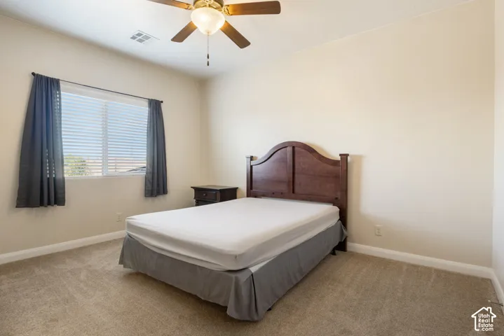Neutral tone wall paint, textured ceiling, ceiling fan with light fixture, carpeted flooring, and a window with blinds