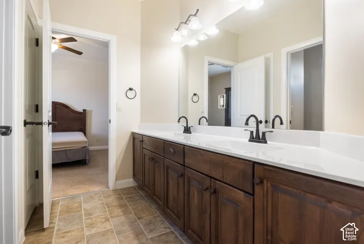 Dual basin vanity with dark wood-finish cabinetry, white solid surface countertop, and matte black fixtures
