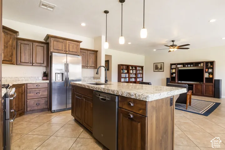 Kitchen island with granite countertop, stainless steel appliances, wood-finish cabinetry, and tiled flooring