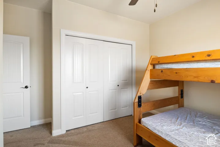 Wall-to-wall carpeting, recessed closet with bi-fold doors, and a ceiling fan