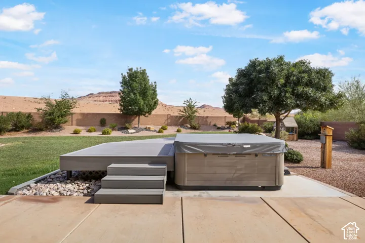 Expansive backyard with a composite deck, integrated hot tub, and a concrete patio